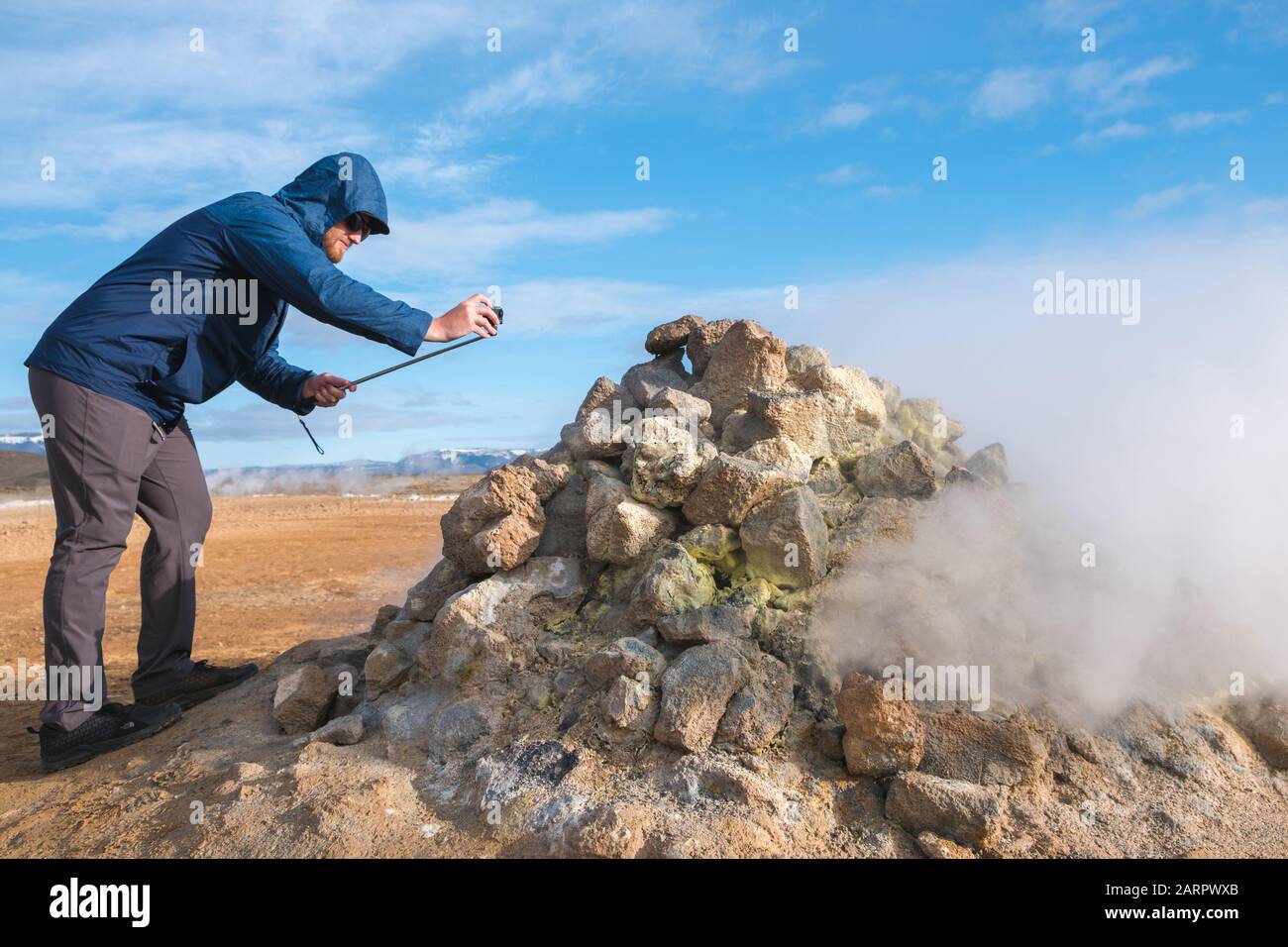American tourist takes a close look at natural fumarole, an opening in or near a volcano, through which hot sulfurous gases emerge Stock Photo