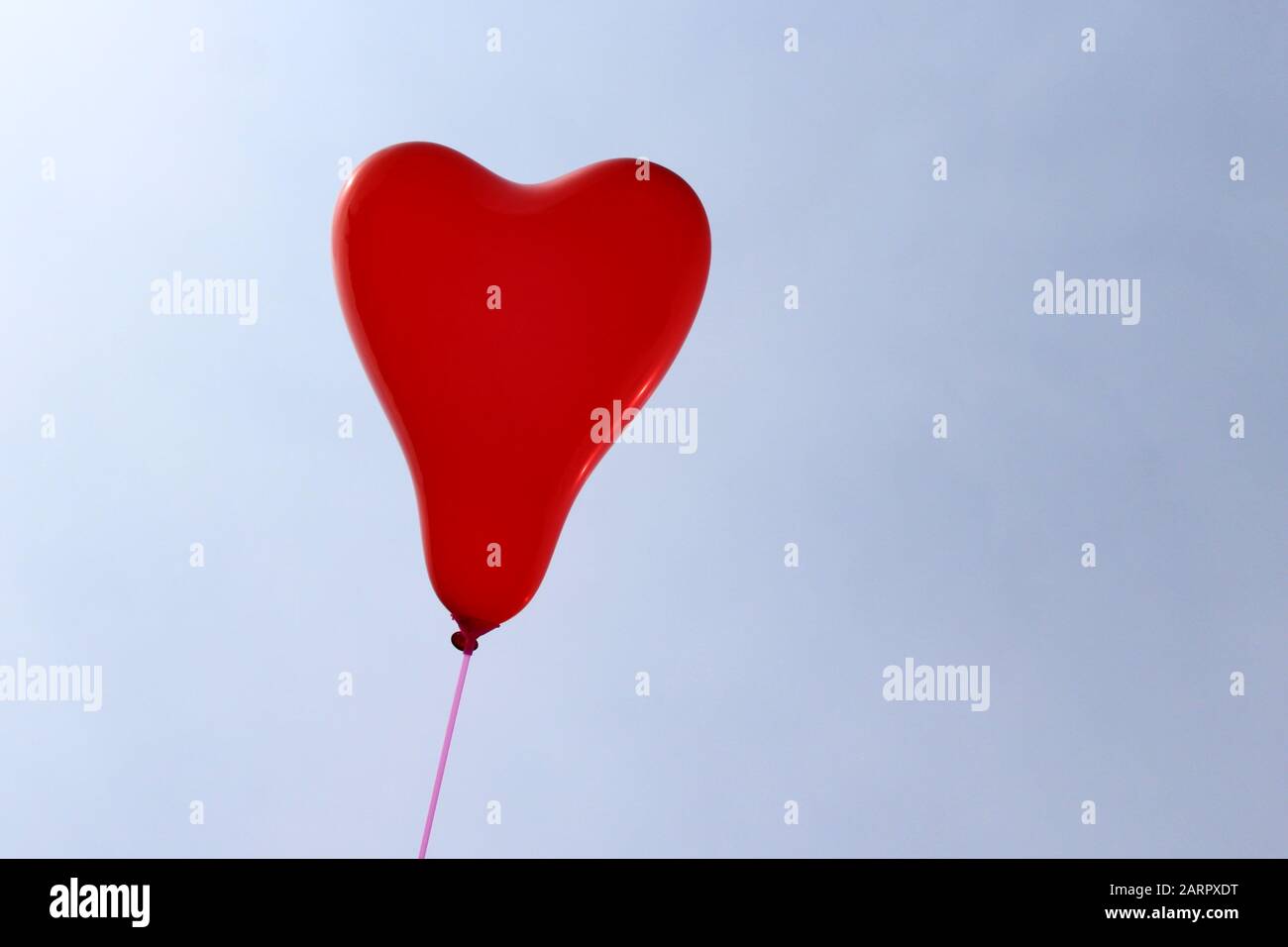 The picture shows a red heart balloon in front of the blue sky Stock ...