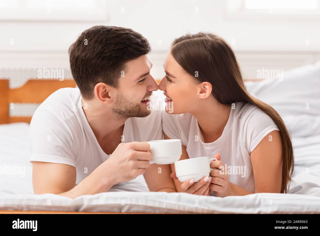 Couple Having Morning Coffee Lying In Bed At Home Stock Photo - Alamy