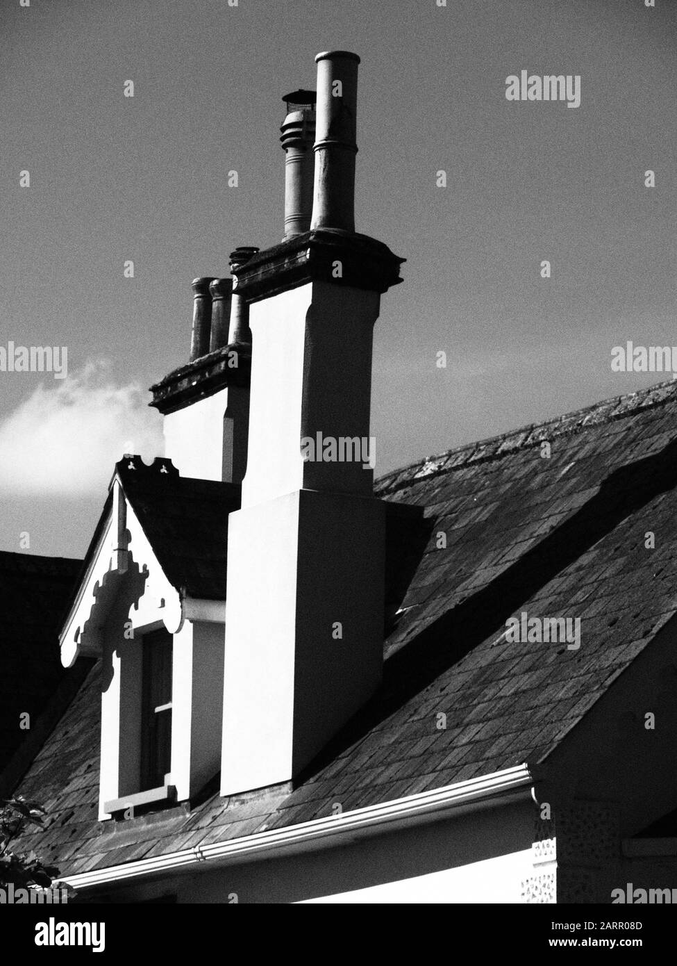 black and white, monochrome, picture of a tall old fashioned house chimney and dormer roof window Stock Photo