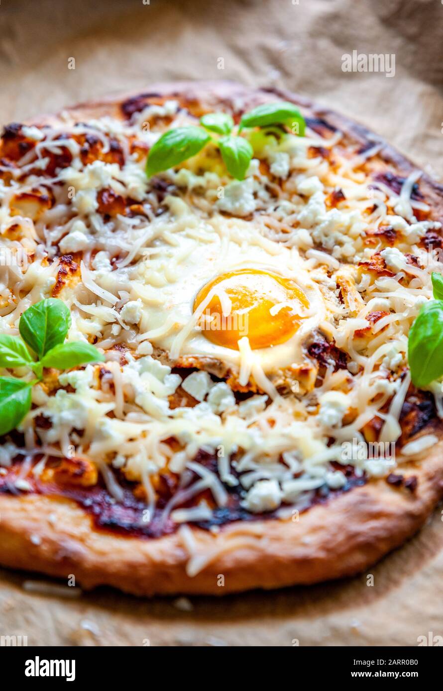 Above shot of a pizza with egg, cheese and herbs. Rustic scene and dramatic light. Stock Photo