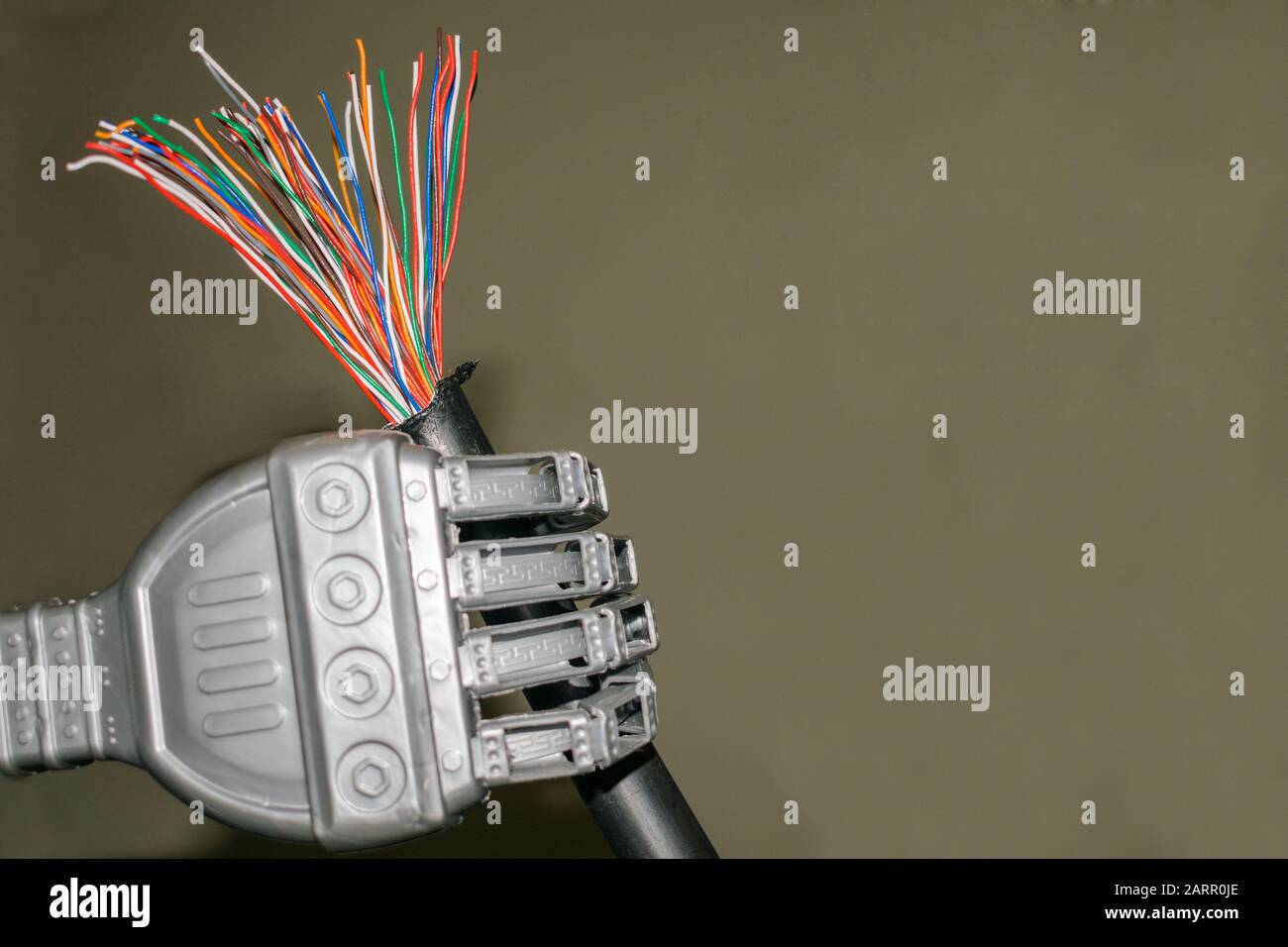 The trunk colored telephone cable is in the robot's hand. Damaged Internet cable close-up Stock Photo