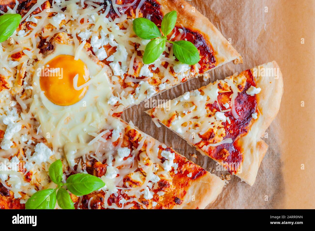 Shot of a pizza with egg, cheese and herbs. Rustic scene and dramatic light. Stock Photo