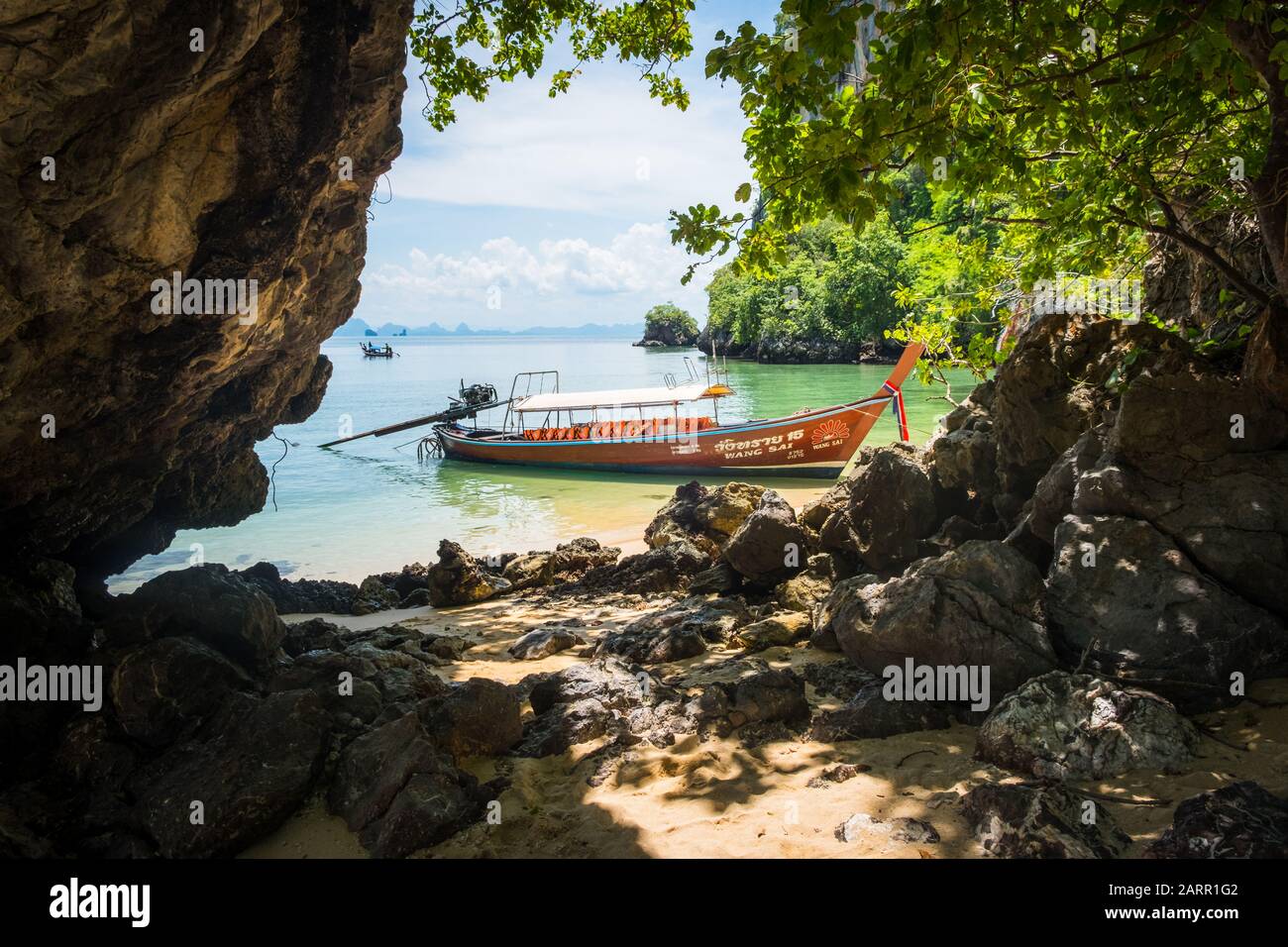 Anchored Thai long tail boat in Phang Nga Bay, Thailand. Karst rock formations in the distance Stock Photo