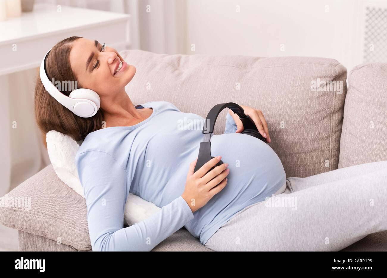 Music and pregnancy. Expectant woman holding headphones near belly Stock  Photo - Alamy
