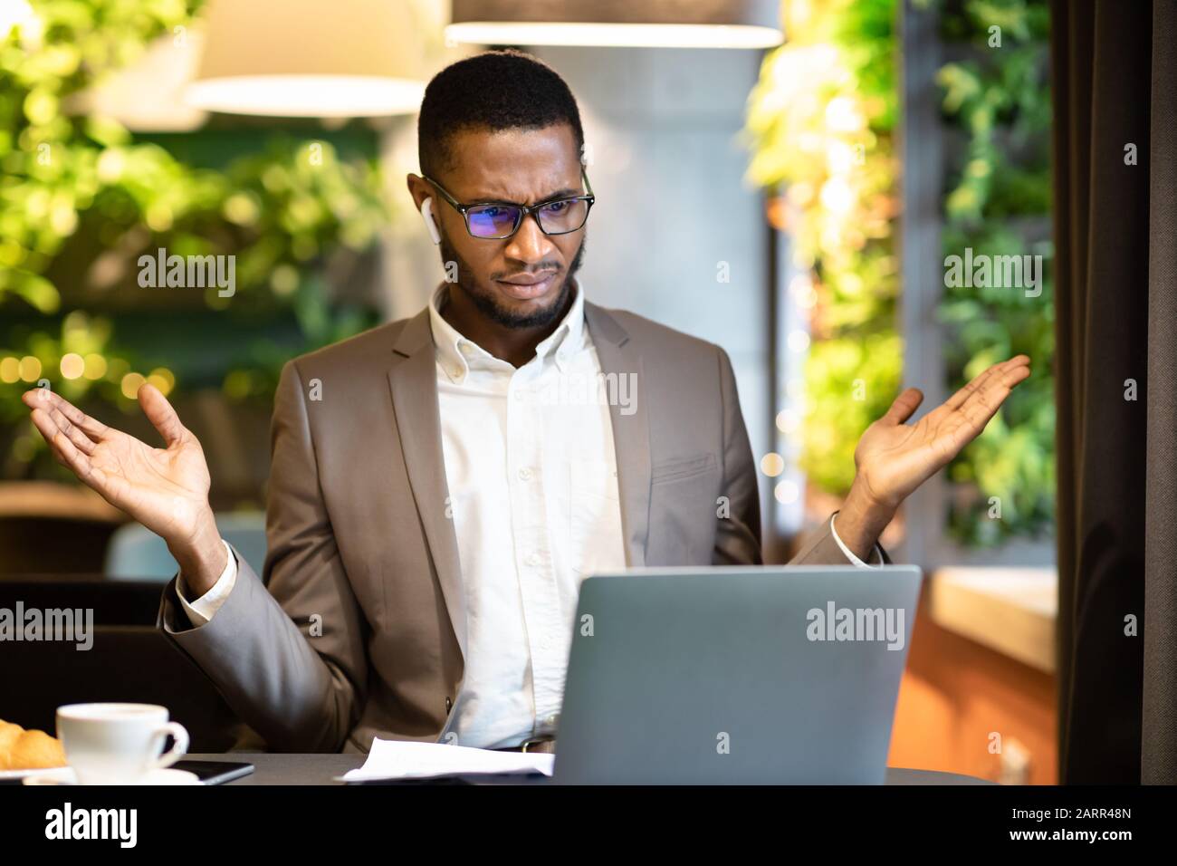 Surprised young afro manager looking at his computer Stock Photo