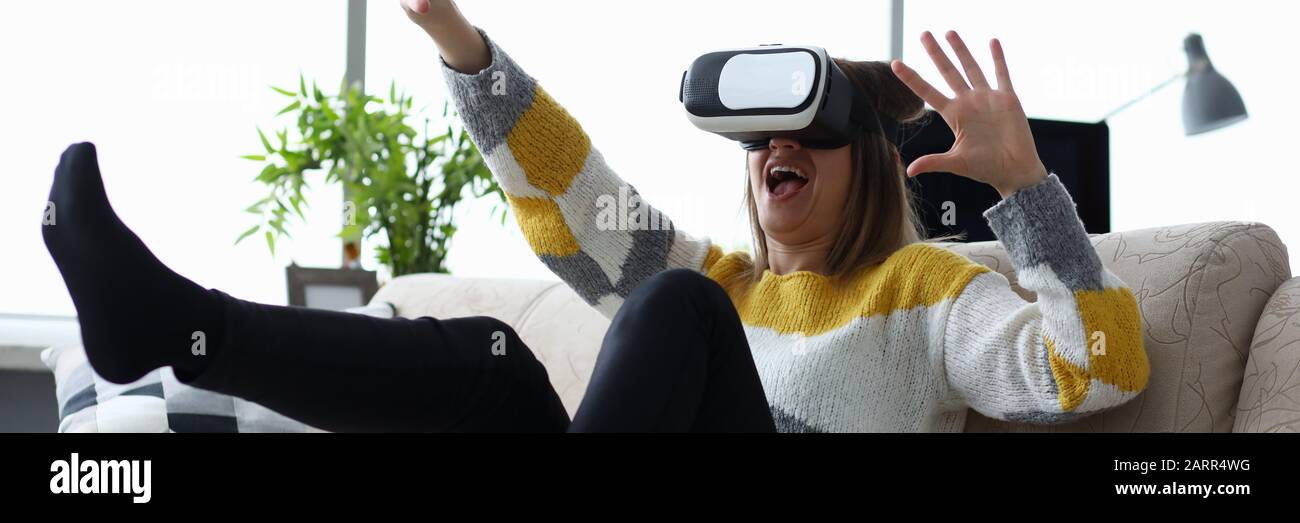 Woman sits at home on the couch uses virtual reality Stock Photo