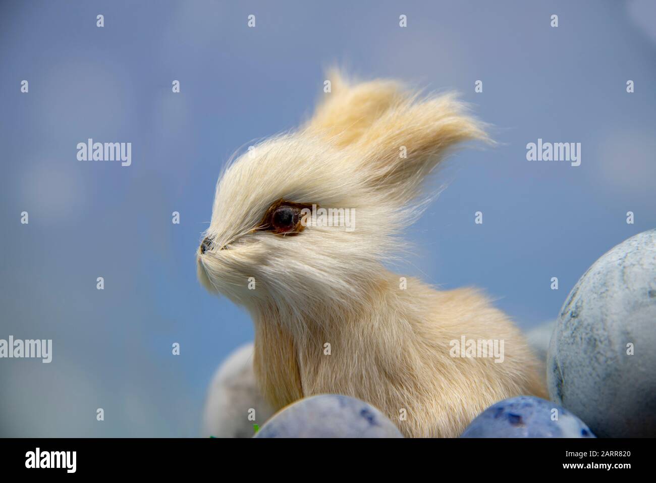 A toy hare and parts of colored eggs on a blue blurred background. Stock Photo