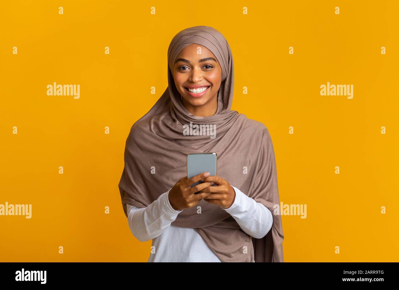 Cheerful Afro Muslim Girl In Hijab With Smartphone In Hands Stock Photo ...