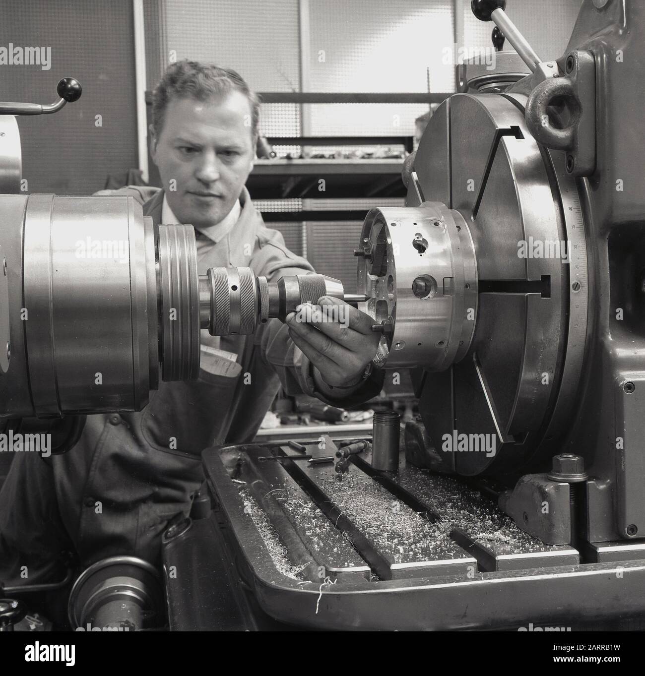 1950s, historical, a engineer using a large machine tool with drill and