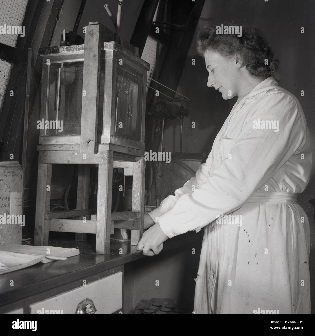 1950s, historical, lady researcher using a wooden and glass cabinet conducting science experiments, England, UK. Stock Photo