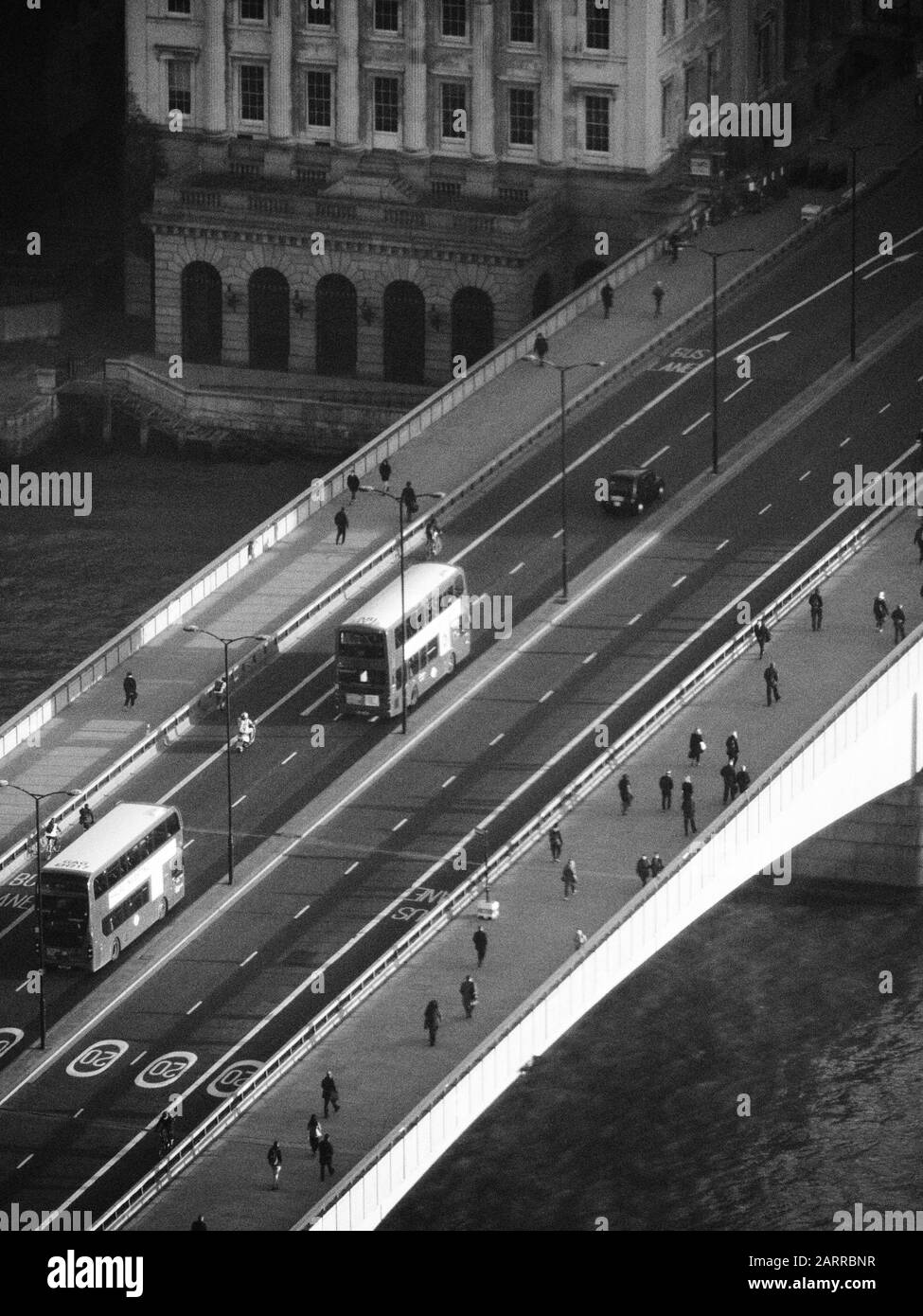 a view looking down onto London Bridge in black and white showing early morning traffic and pedestrians crossing Stock Photo