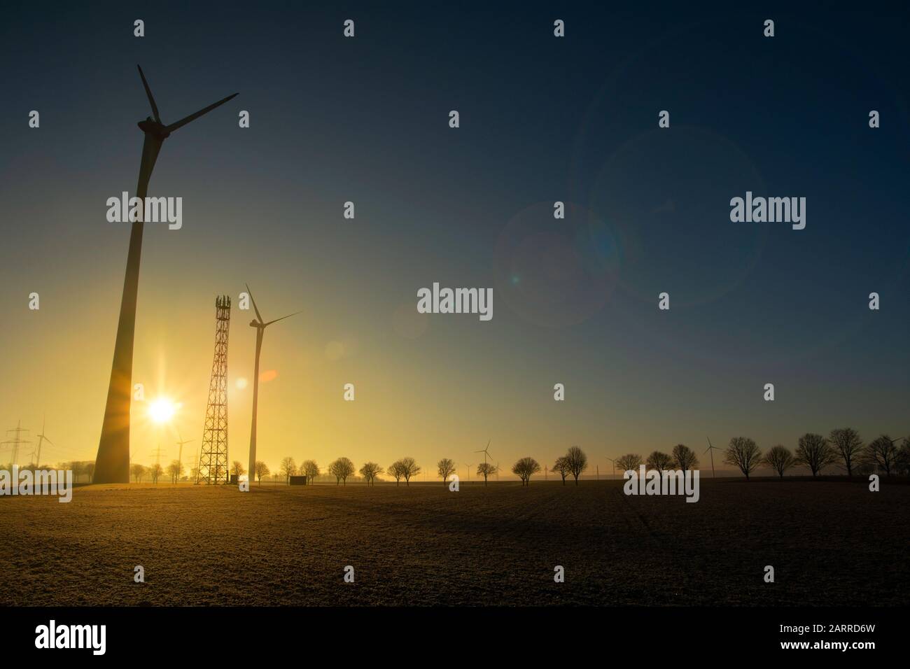 Wind turbines at sunset with blue, yellow and  violet colors on a meadow, concept of ecological energy, climate change, renewable energy Stock Photo