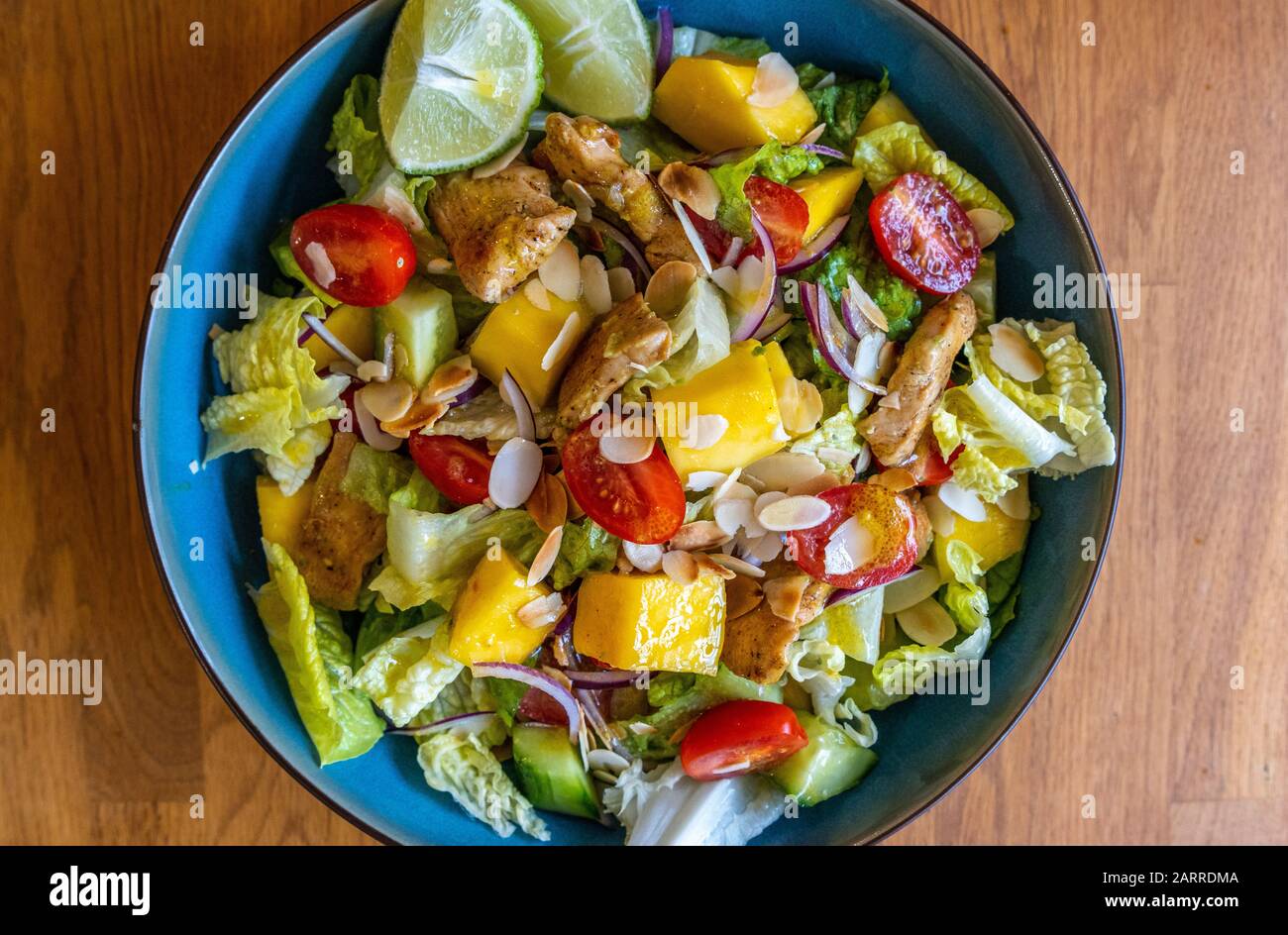 Overhead shot of a mango salad with roasted chicken, lettuce, red onion and lime Stock Photo