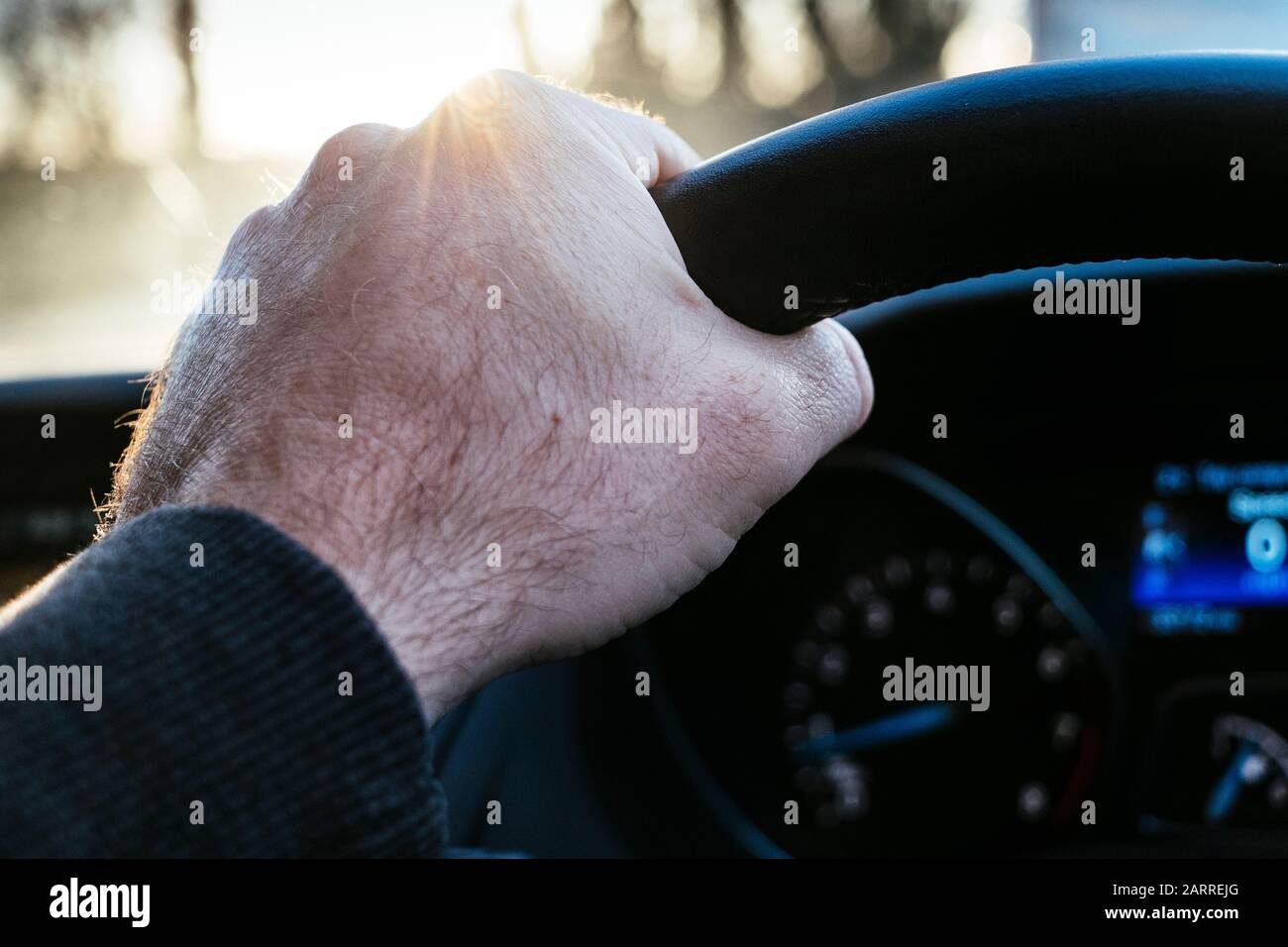 A male hand on the steering wheel of a car Stock Photo