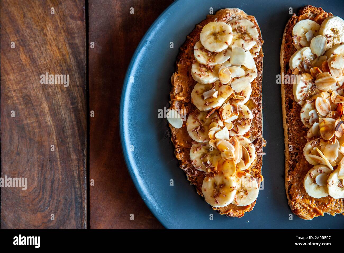 Close up shot of a slices of bread topped with peanut butter, honey and banana slices Stock Photo