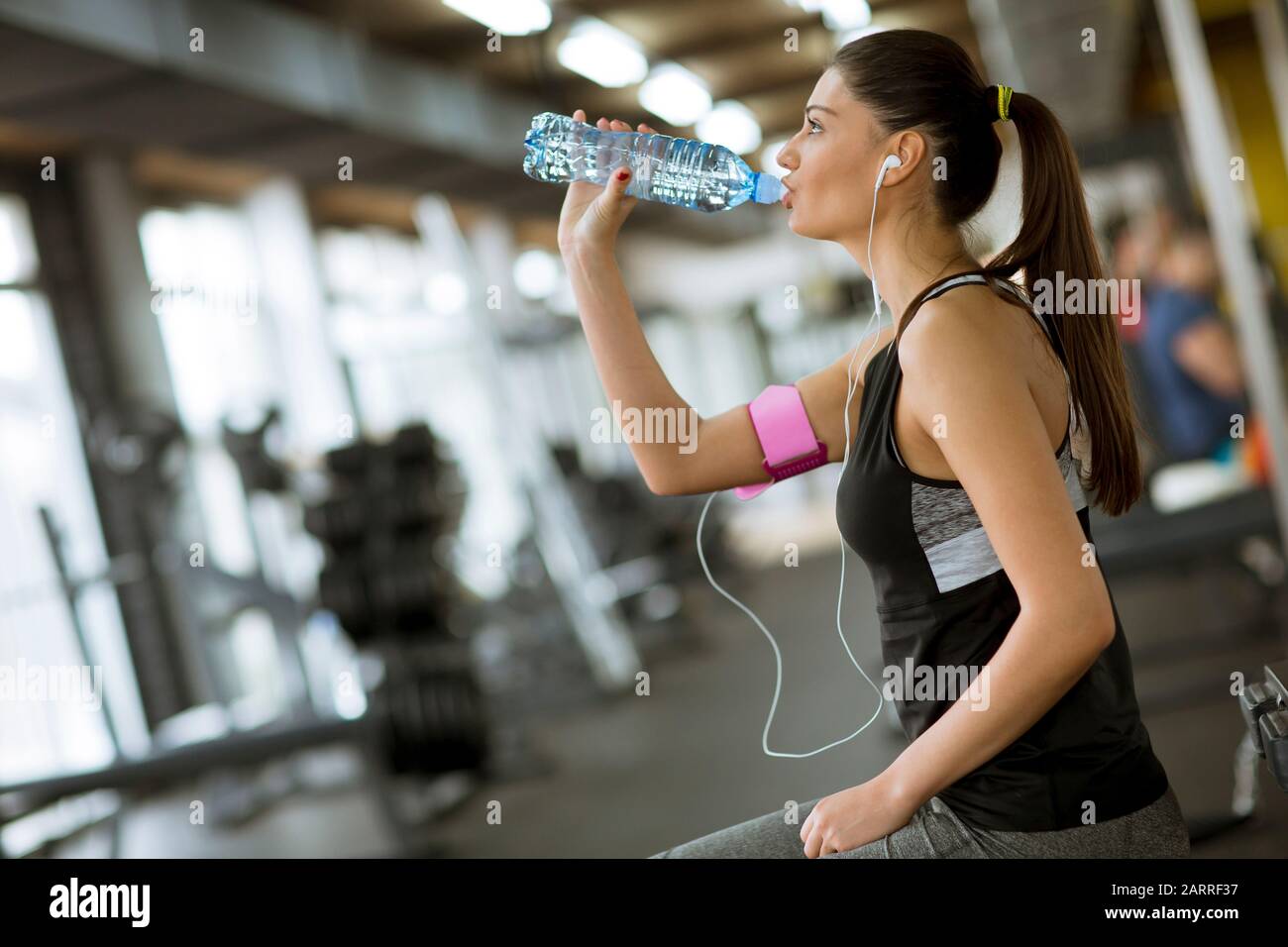 Attractive sport young woman drinking water while sitting and resting after  workout in the gym Stock Photo - Alamy, image size:1300x956