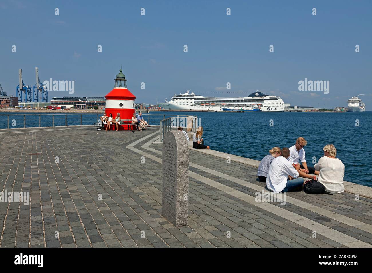 Young people on the Langelinie pier-head in Copenhagen. View to cruise ships in Nordhavn and the new cruise terminal. Theresienstadt memorial in front Stock Photo