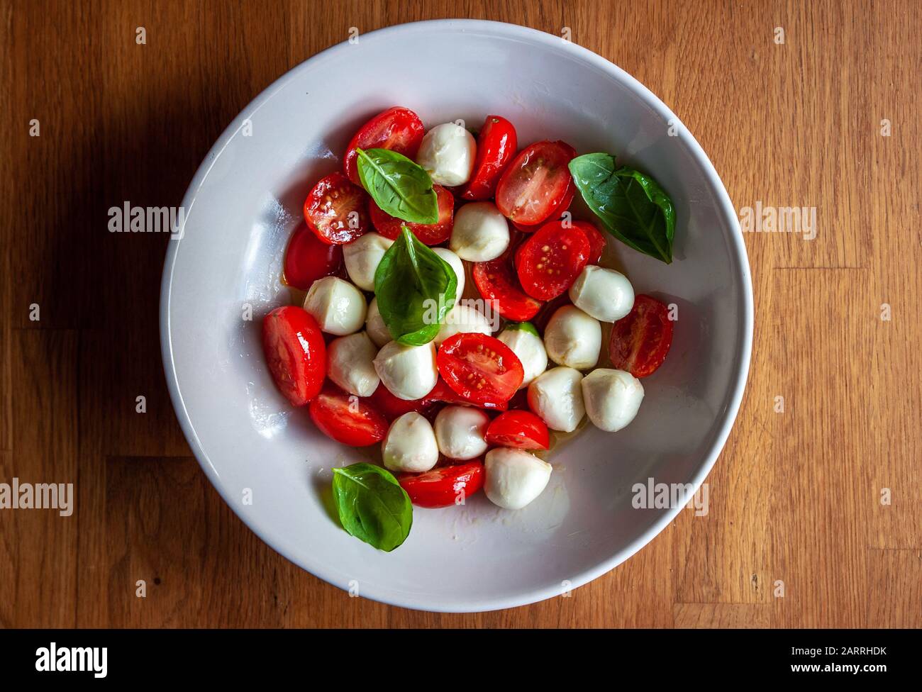 Overhead shot of a bowl of tomato salad with mozzarella cheese and fresh basil Stock Photo