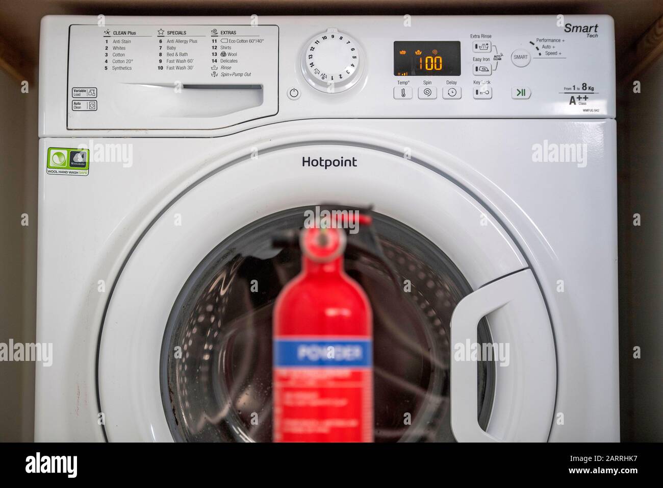 A Hotpoint washing machine which is on a recall list of fire-prone  appliances with a fire extinguisher. This is one of a host of machines that  may catch fire owing to an