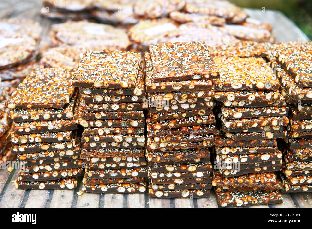 A pile of peanut brittle bars covered with sesame seeds laying for sale
