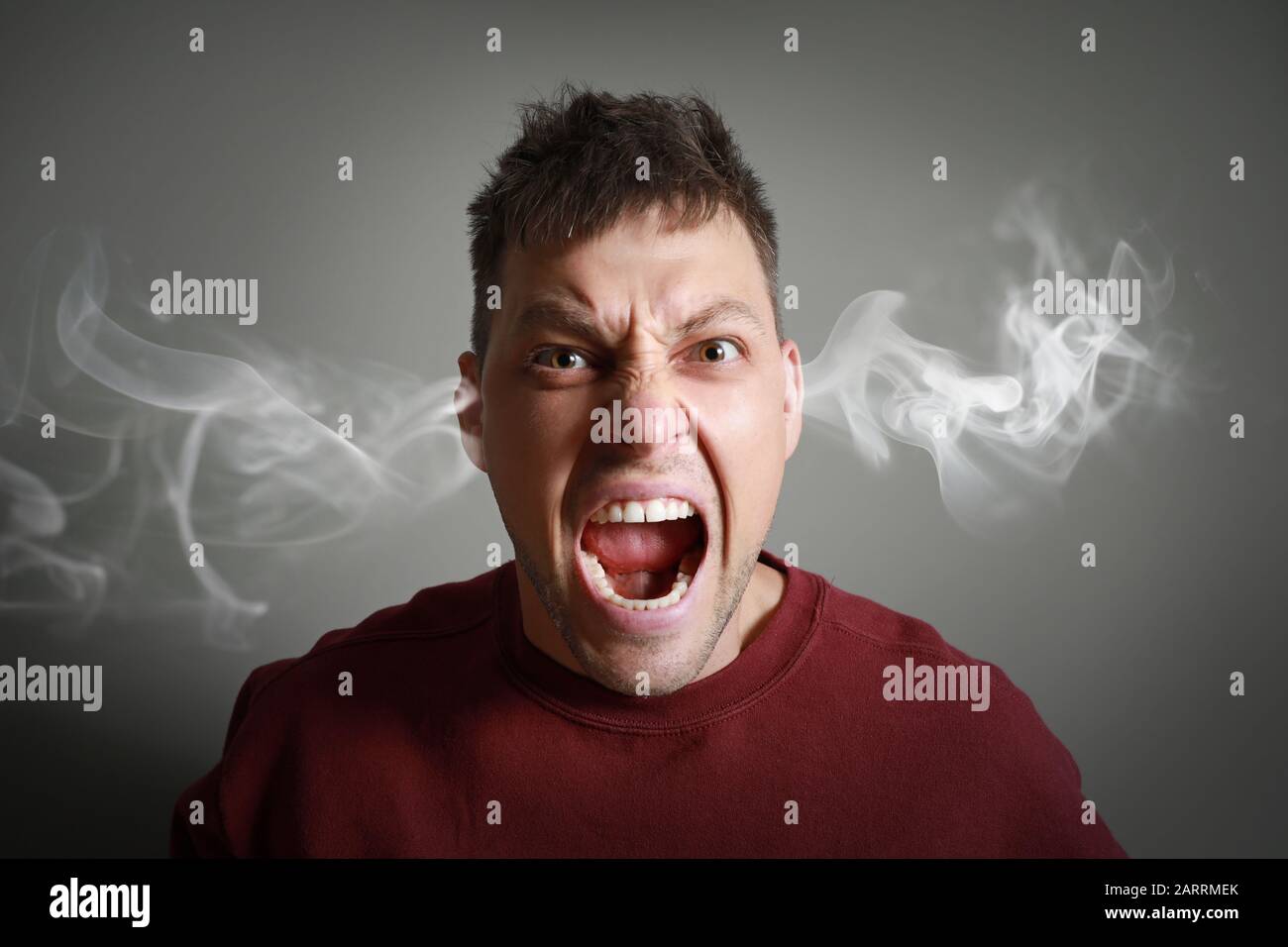 Portrait of angry man with steam coming out of ears on grey background Stock Photo