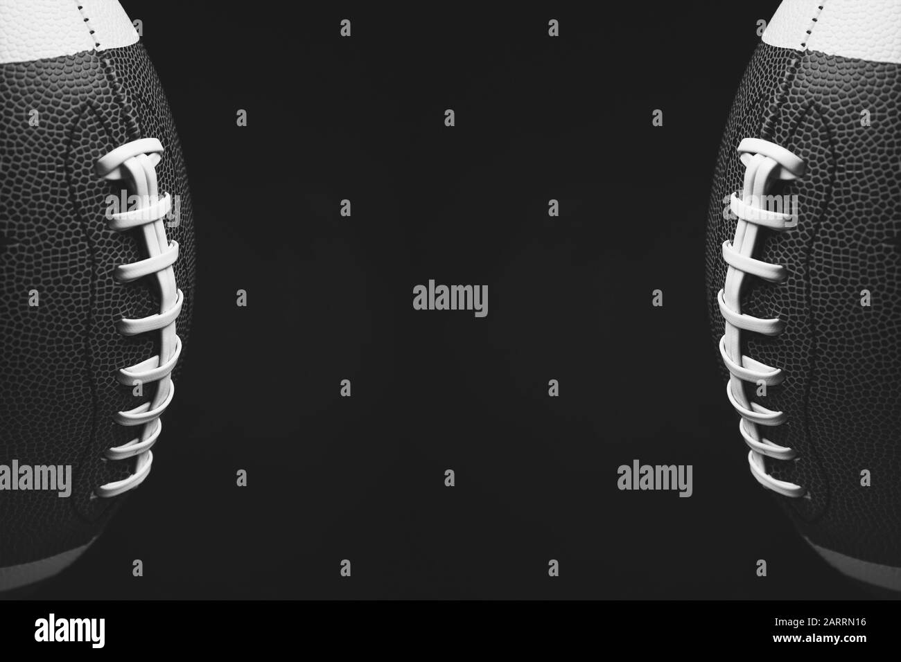 Black and white photo of rugby balls on dark background with space for text Stock Photo
