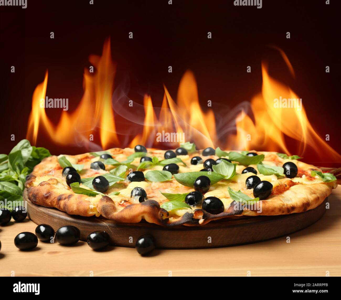 Hot pizza with burning flame on table against dark background Stock