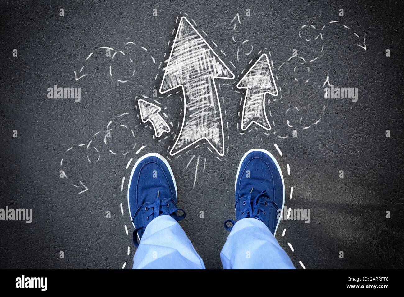 Person standing on asphalt road near arrows pointing in different ...