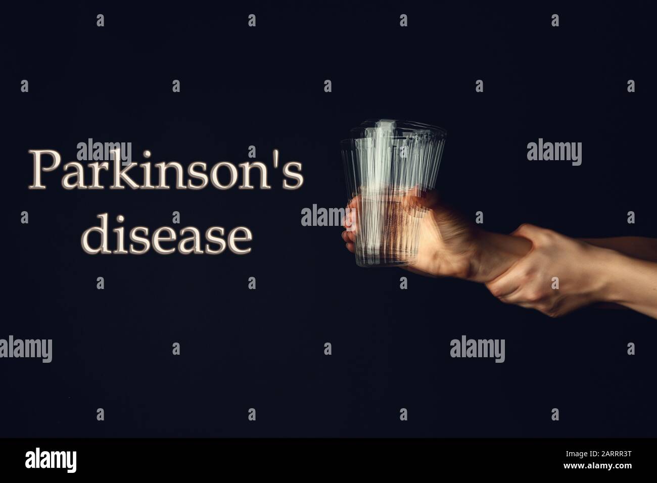 Trembling hands with glass of water and text PARKINSON'S DISEASE on dark background Stock Photo