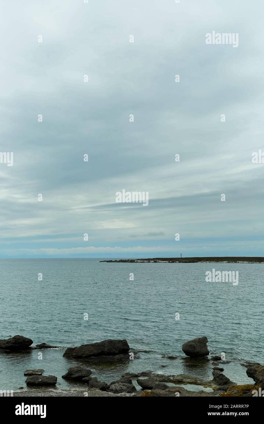 Ocean with Rocky Shore and Lighthouse with a cloudy sky Stock Photo - Alamy