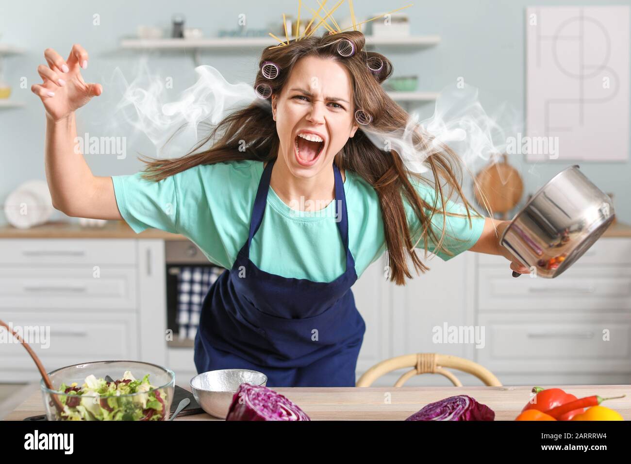 Aggressive young housewife with steam coming out of ears in kitchen Stock Photo