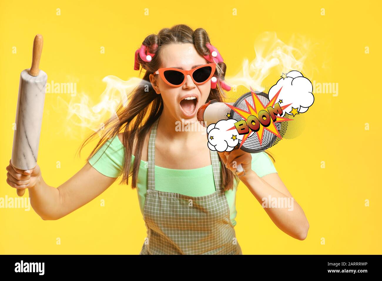 Funny housewife with steam coming out of ears, rolling pin and megaphone on color background Stock Photo