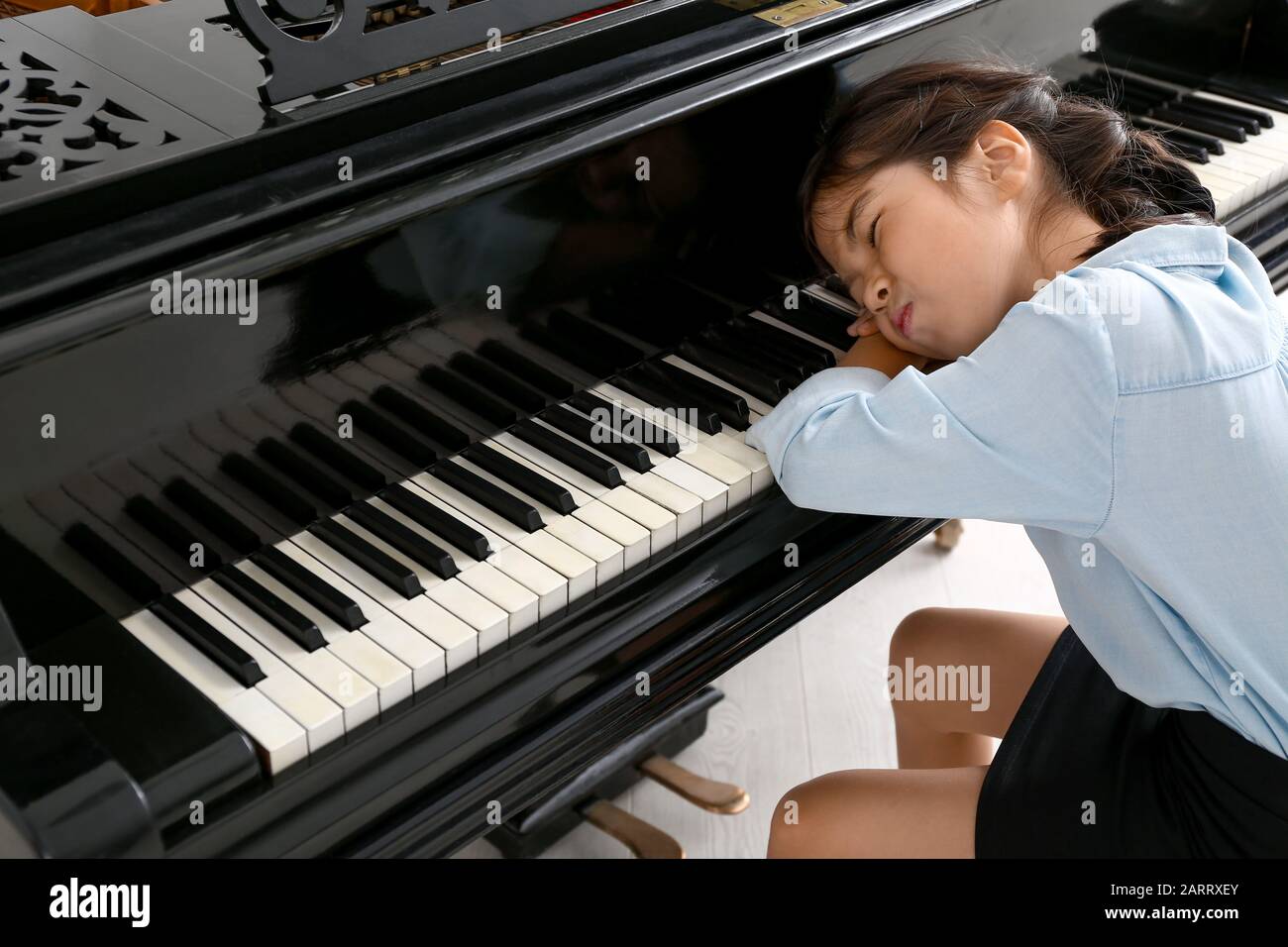 Displeased little girl refusing to play piano at home Stock Photo - Alamy