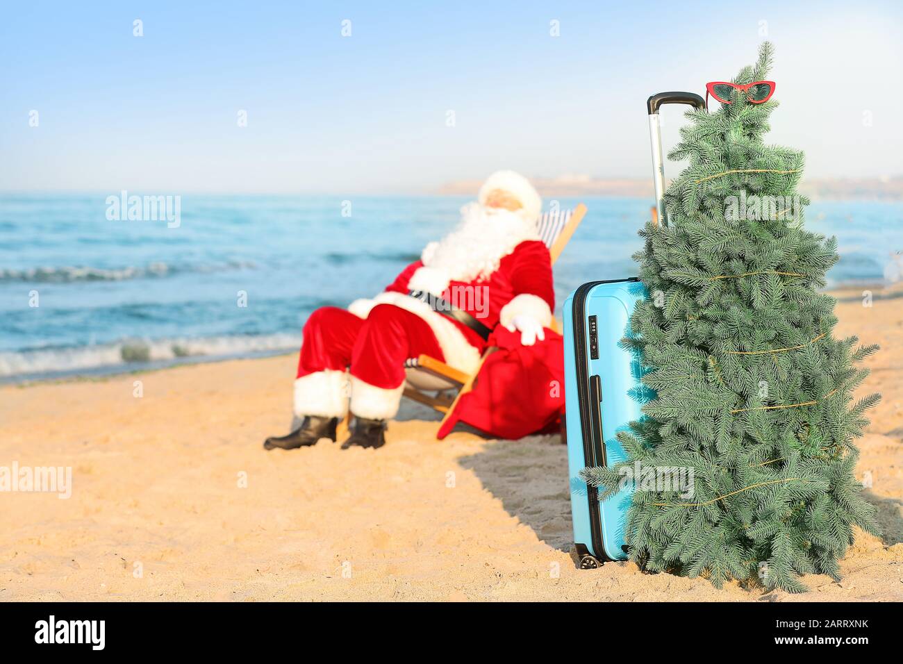 Santa Claus with luggage and fir tree resting at sea resort Stock Photo ...