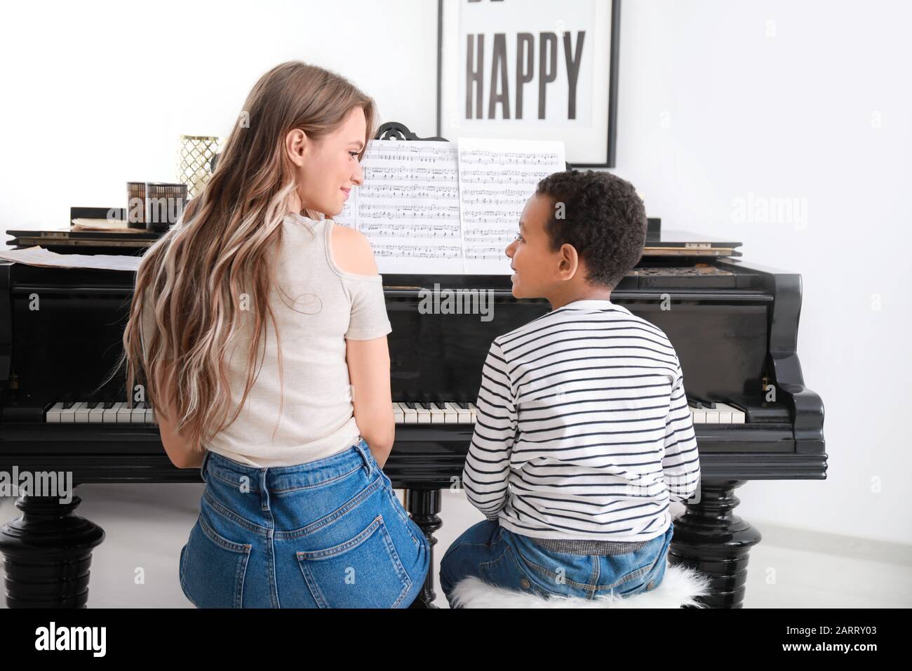 Woman teaching little African-American boy to play piano at home Stock Photo