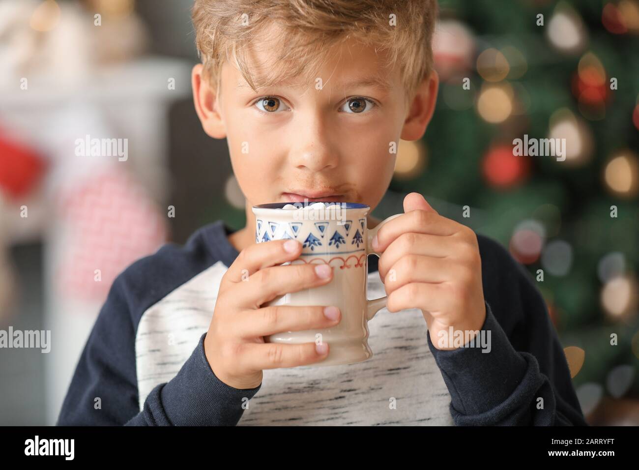 Cute little boy drinking hot chocolate at home on Christmas eve Stock