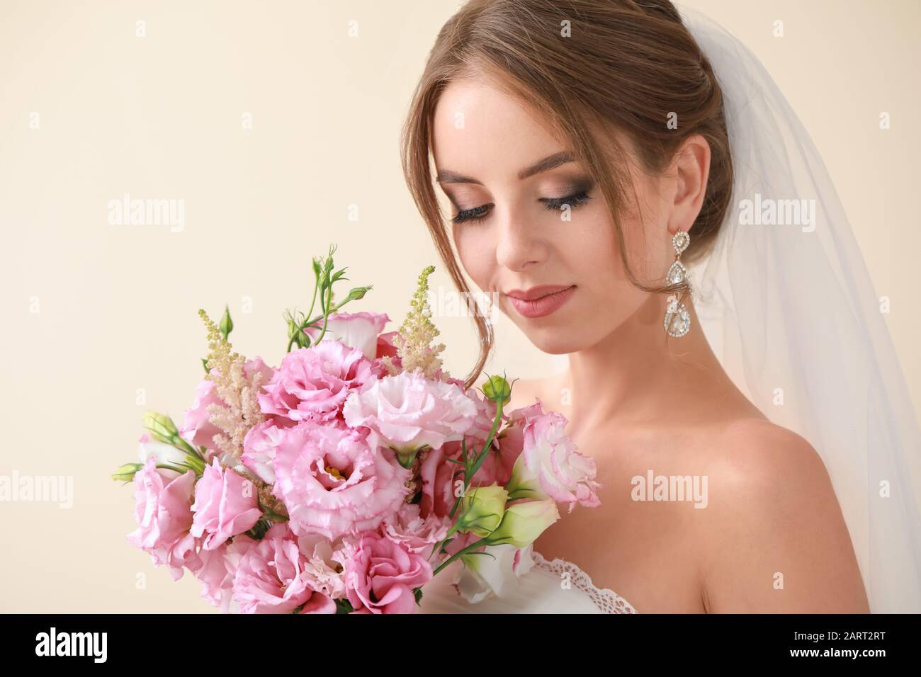 Portrait of beautiful young bride with wedding bouquet on light ...