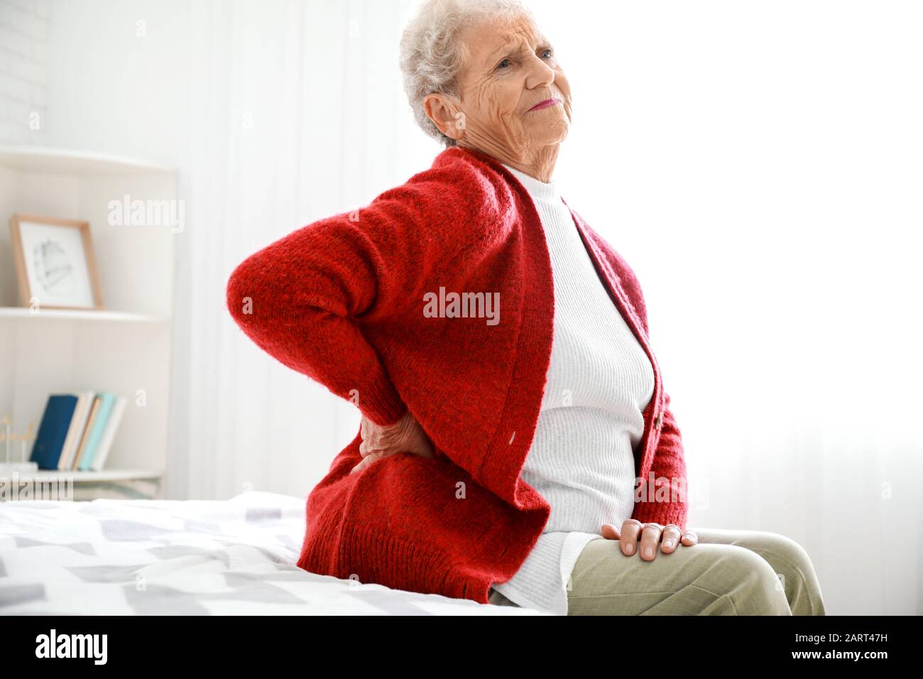 Senior woman suffering from pain in back at home Stock Photo - Alamy