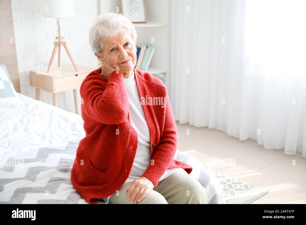 Senior woman suffering from pain in neck at home Stock Photo - Alamy