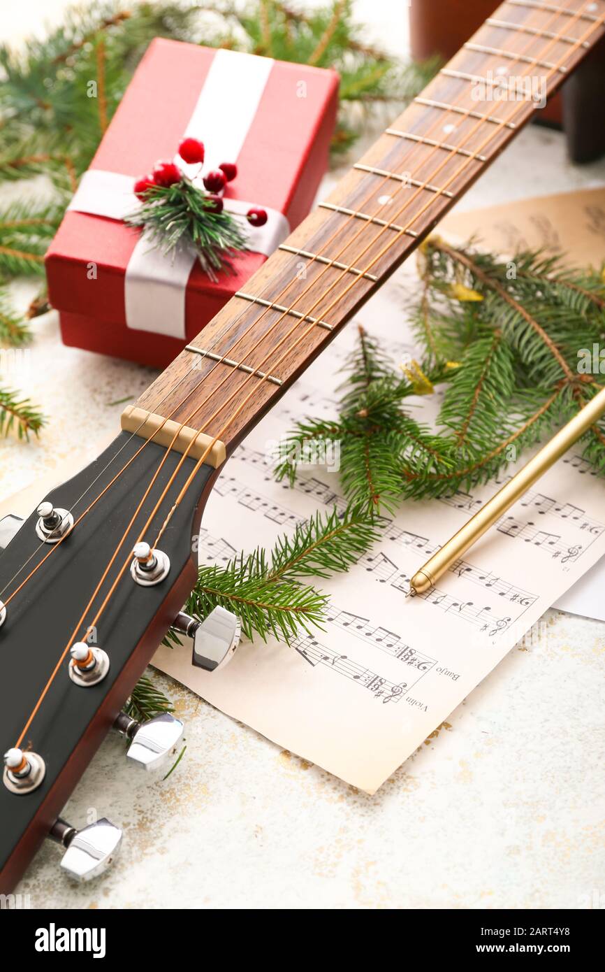 Guitar, note sheets, gift and Christmas decor on table Stock Photo