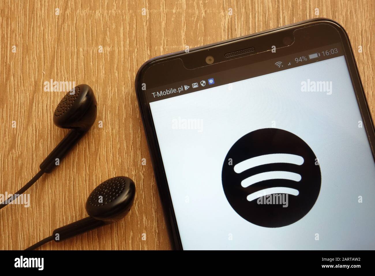 Spotify logo displayed on a modern smartphone and earphones Stock Photo