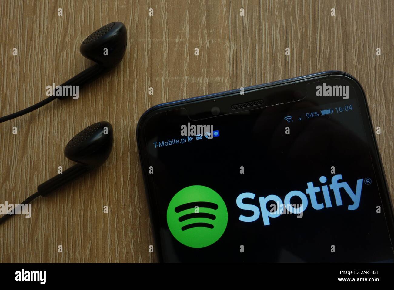 Spotify logo displayed on a modern smartphone and earphones Stock Photo