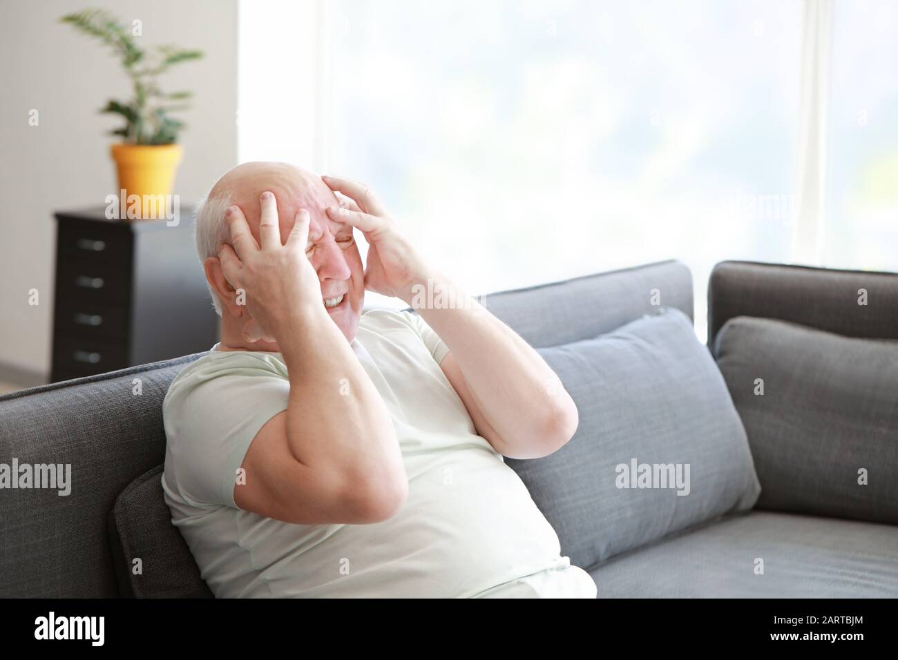 Senior man suffering from headache at home Stock Photo - Alamy
