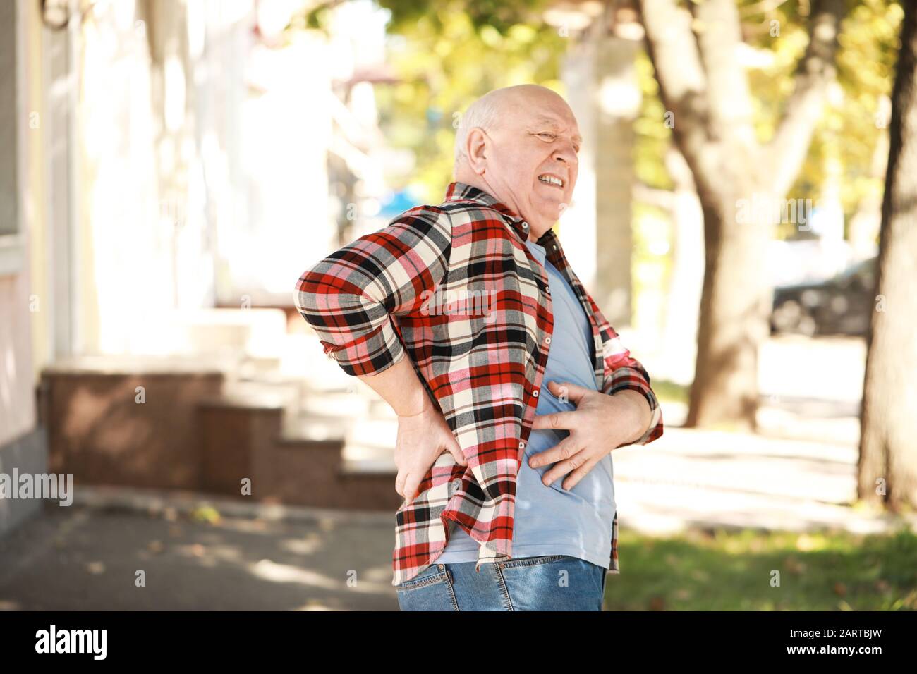 Senior man suffering from back pain outdoors Stock Photo - Alamy