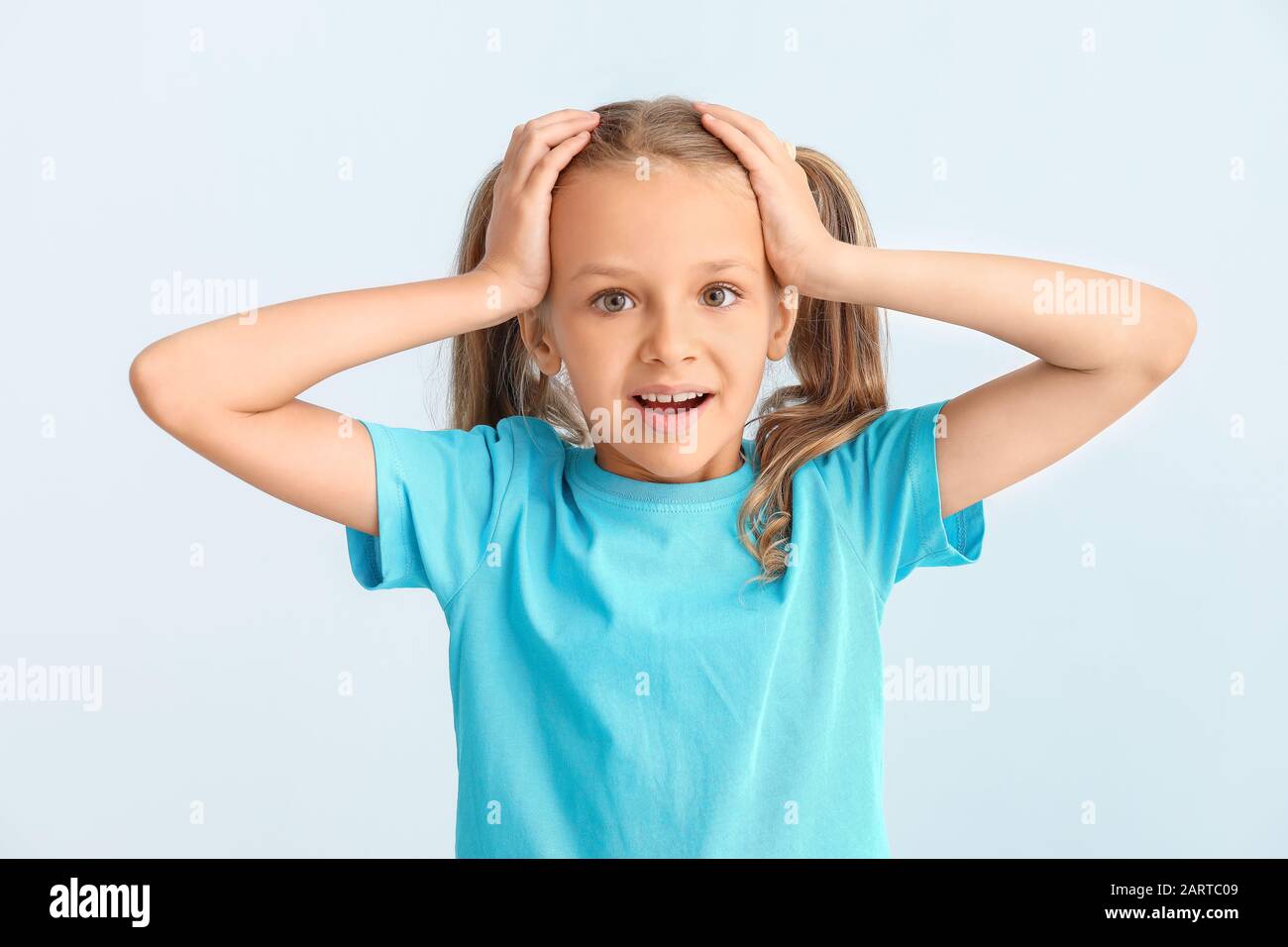 Surprised little girl on light background Stock Photo - Alamy