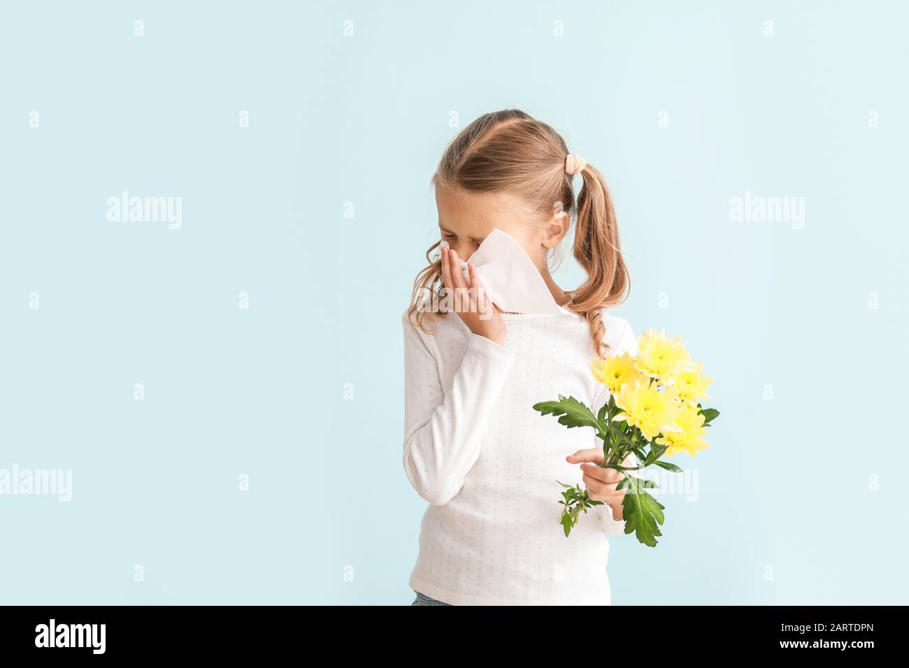 Little girl suffering from allergy to flowers on light background Stock Photo