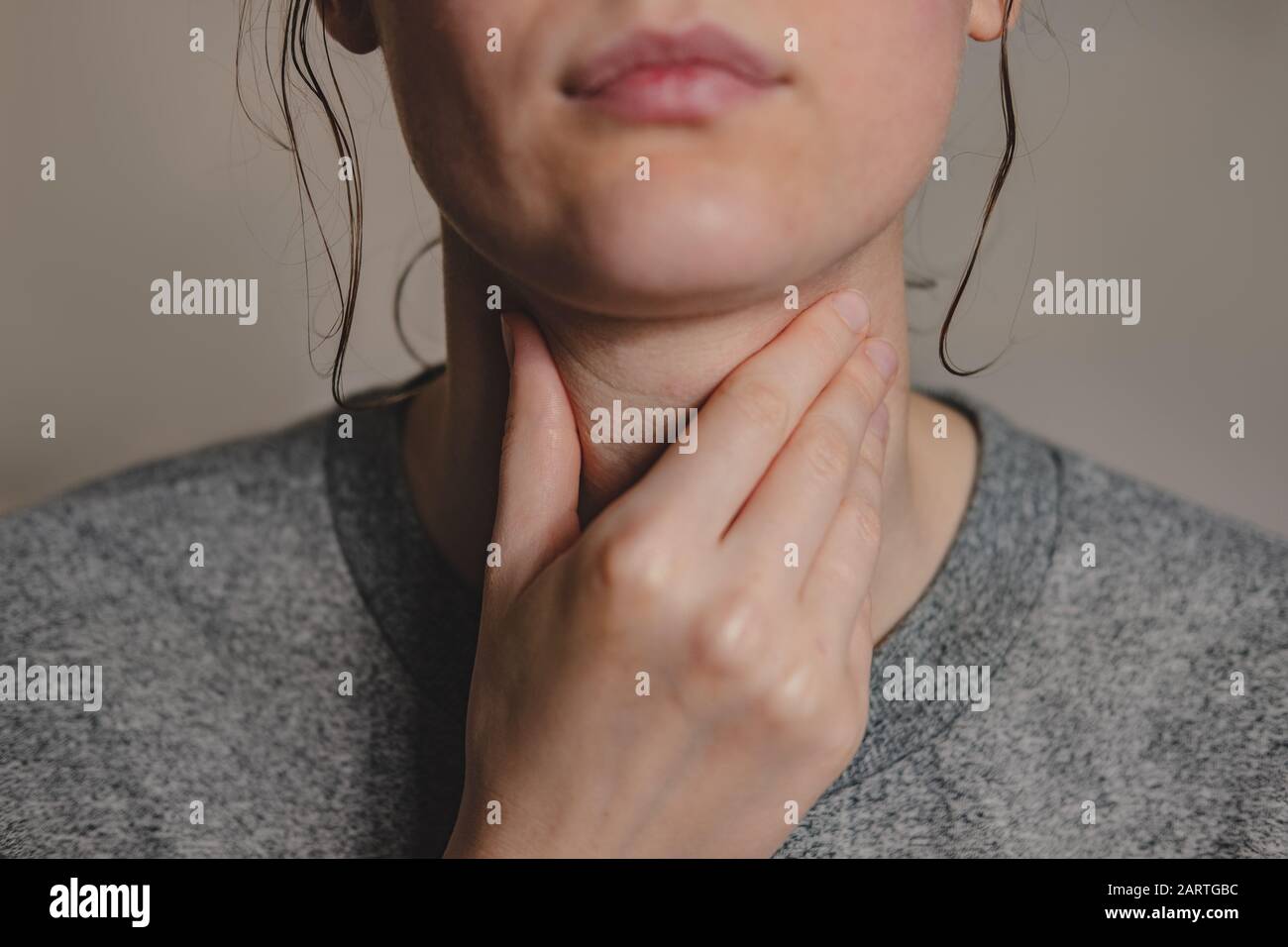 Sore throat, virus disease or flu. Woman holds hand against her throat