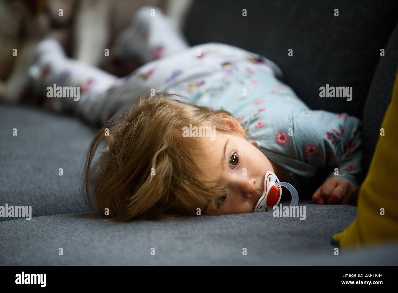 Cute 2 year old Baby girl on a bed on her belly with head on sofa