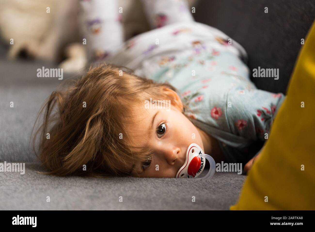 Cute 2 year old Baby girl on a bed on her belly with head on sofa
